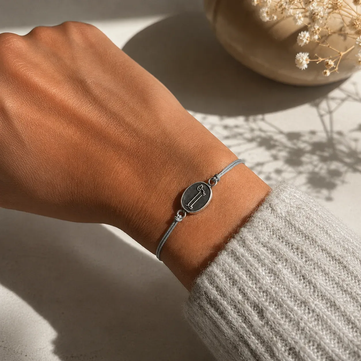 Franzband mit Dackel aus Silber, am Handgelenk getragen, graues Band